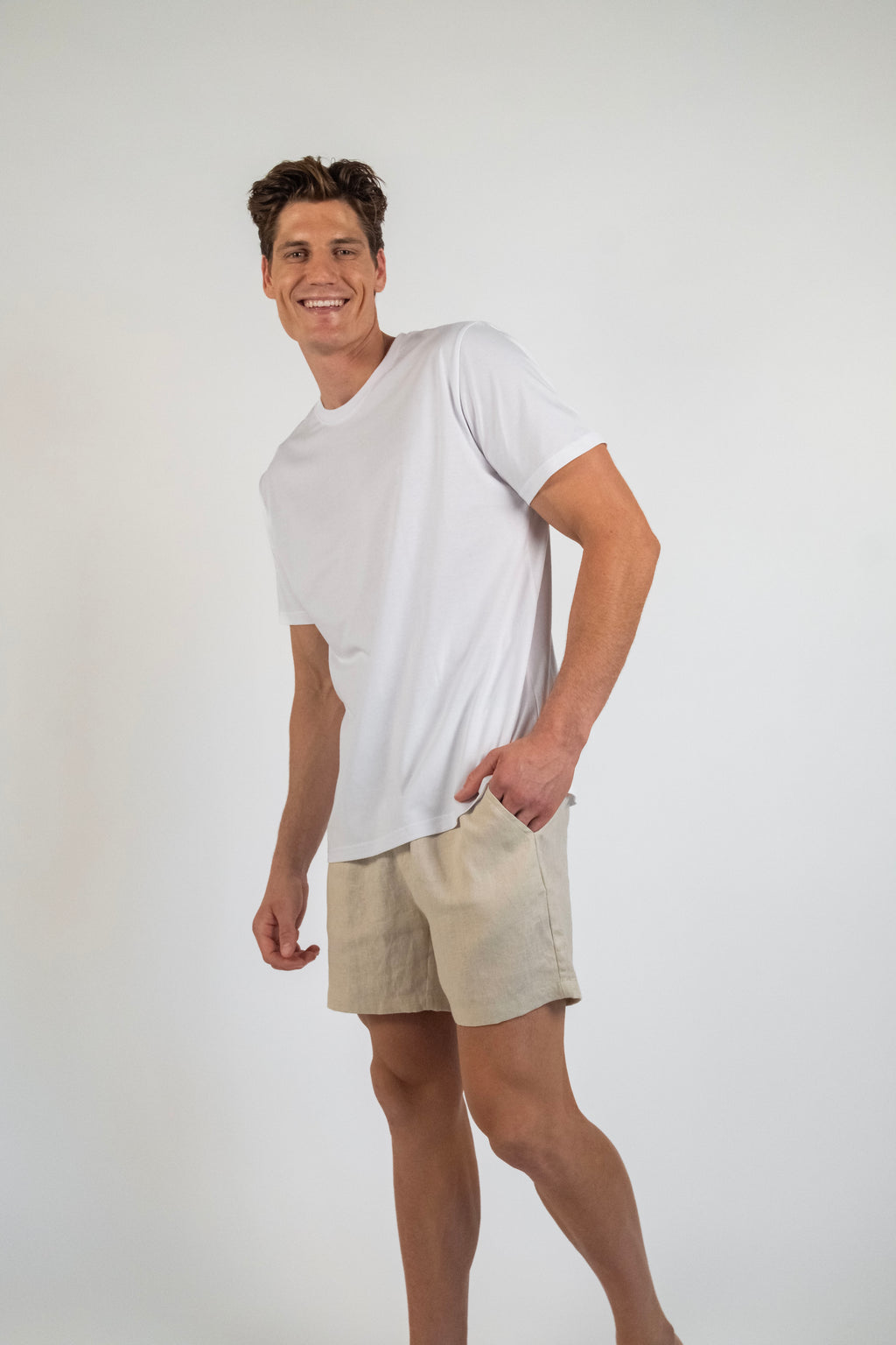 Man wearing a white t-shirt and beige shorts on a plain background