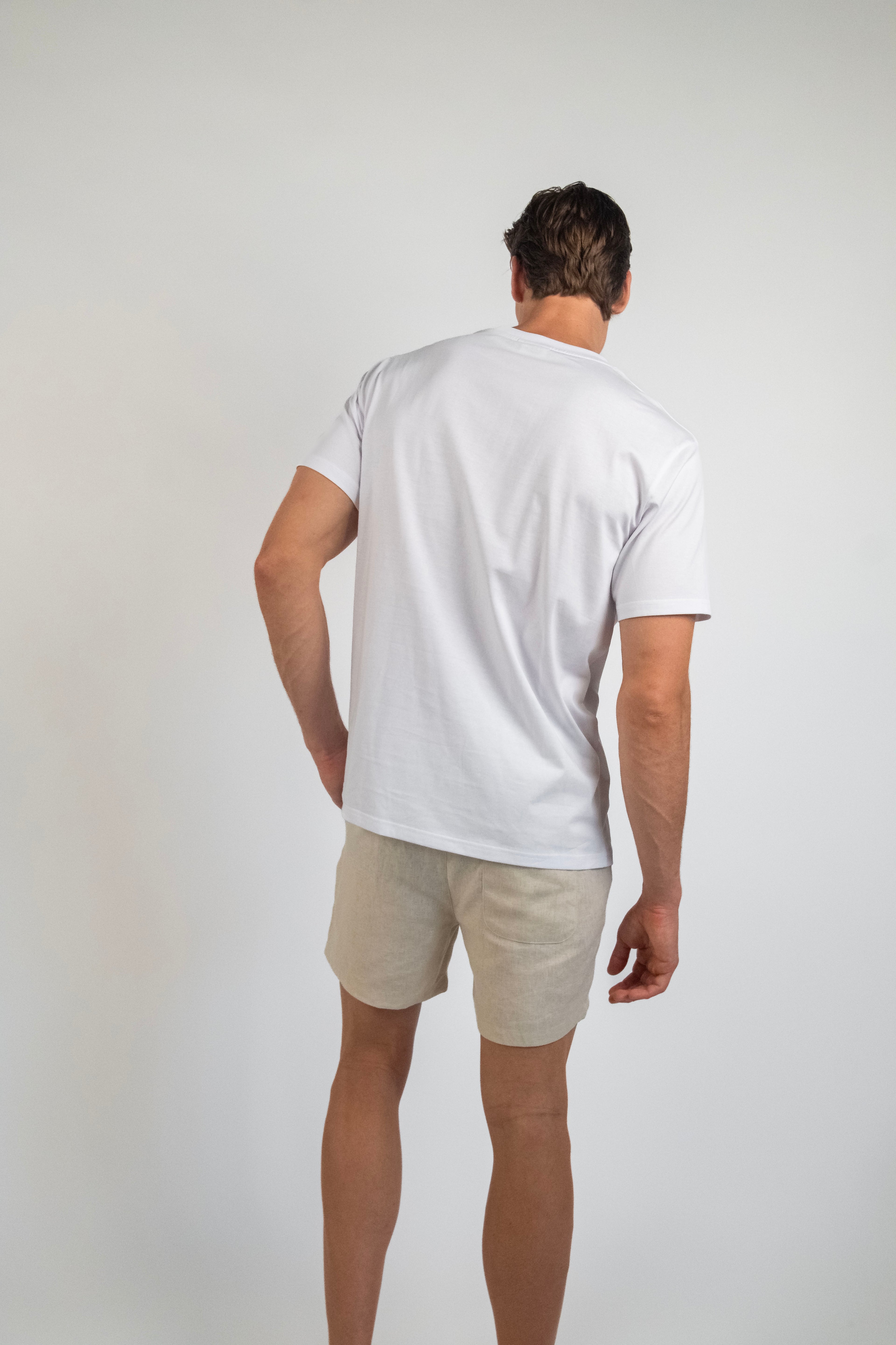 Person wearing a white t-shirt and beige shorts on a plain background